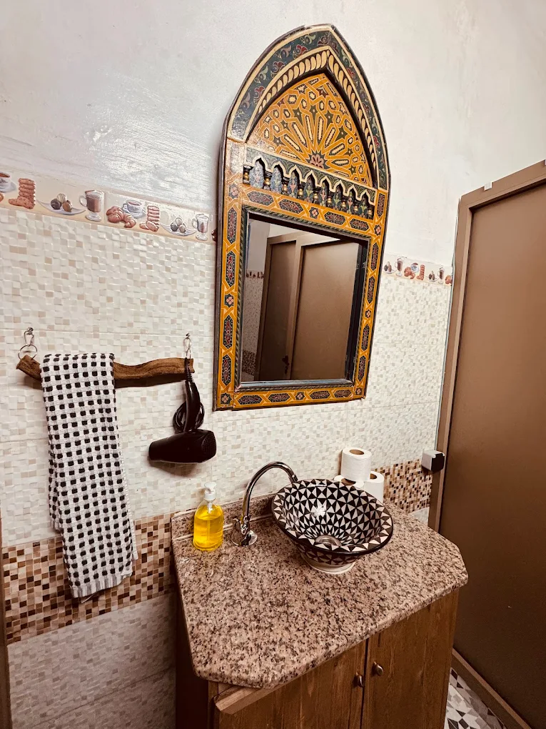 Lavabo decorado y espejo artesanal — baño de riad en Essaouira