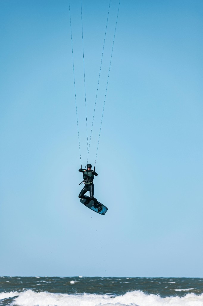 Kitesurfista en salto sobre el agua, cielo azul — acción kite Essaouira.