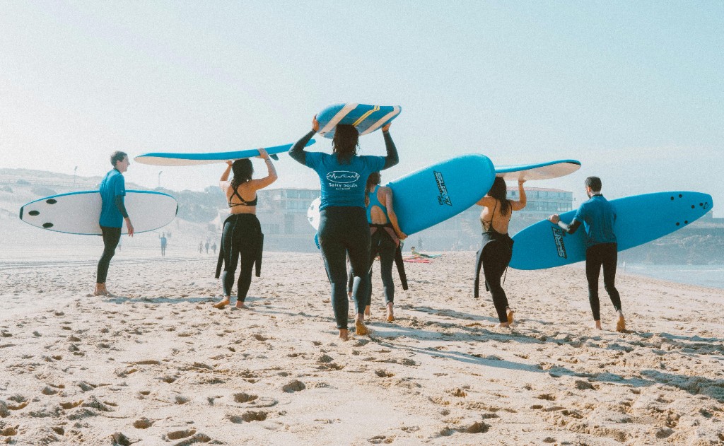 Grupo de surfistas con monitor en selfie y tablas azules en la bahia de Essaouira.