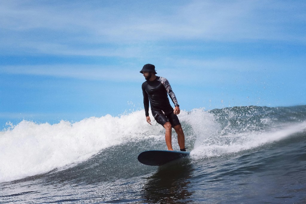 Surfista con neopreno negro en una ola limpia bajo cielo azul, sesión de surf en Essaouira.