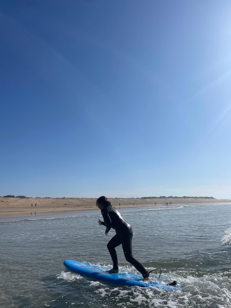 Principiante surfeando ola pequeña con tabla azul soft — sesión playa Essaouira.