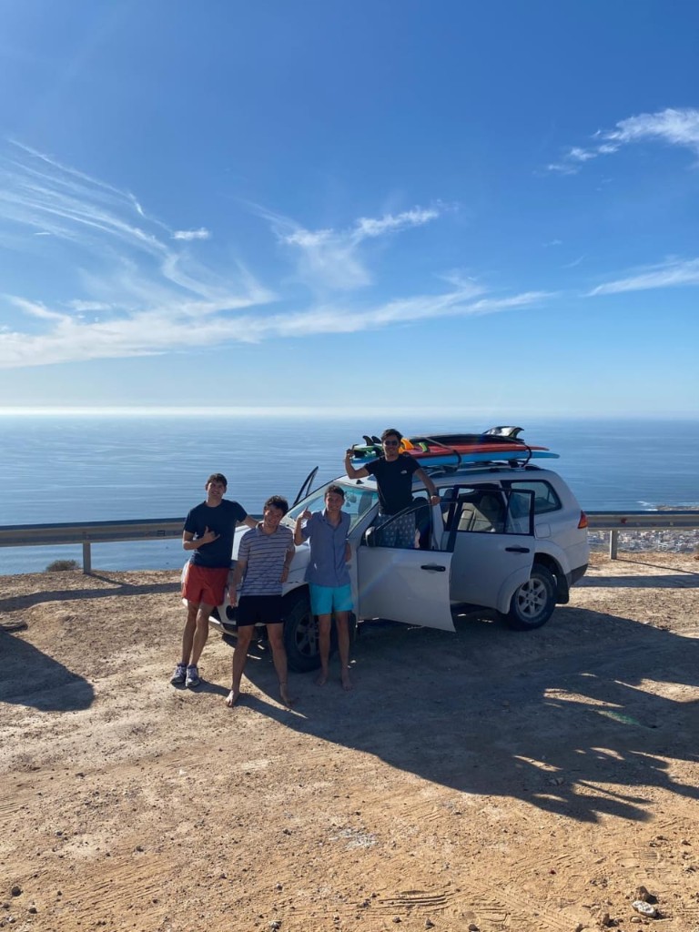 Equipo y 4x4 blanco con tablas en carretera costera — traslado al spot