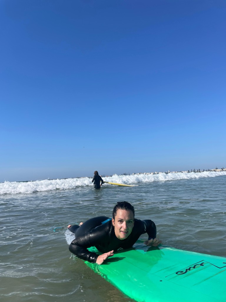 Tumbada remando en tabla verde durante clase de surf — Essaouira.
